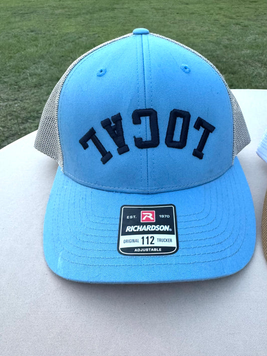 Blue structured hat with beigh mesh with the word LOCAL embroidered across the hat upside down with pukk navy words 
