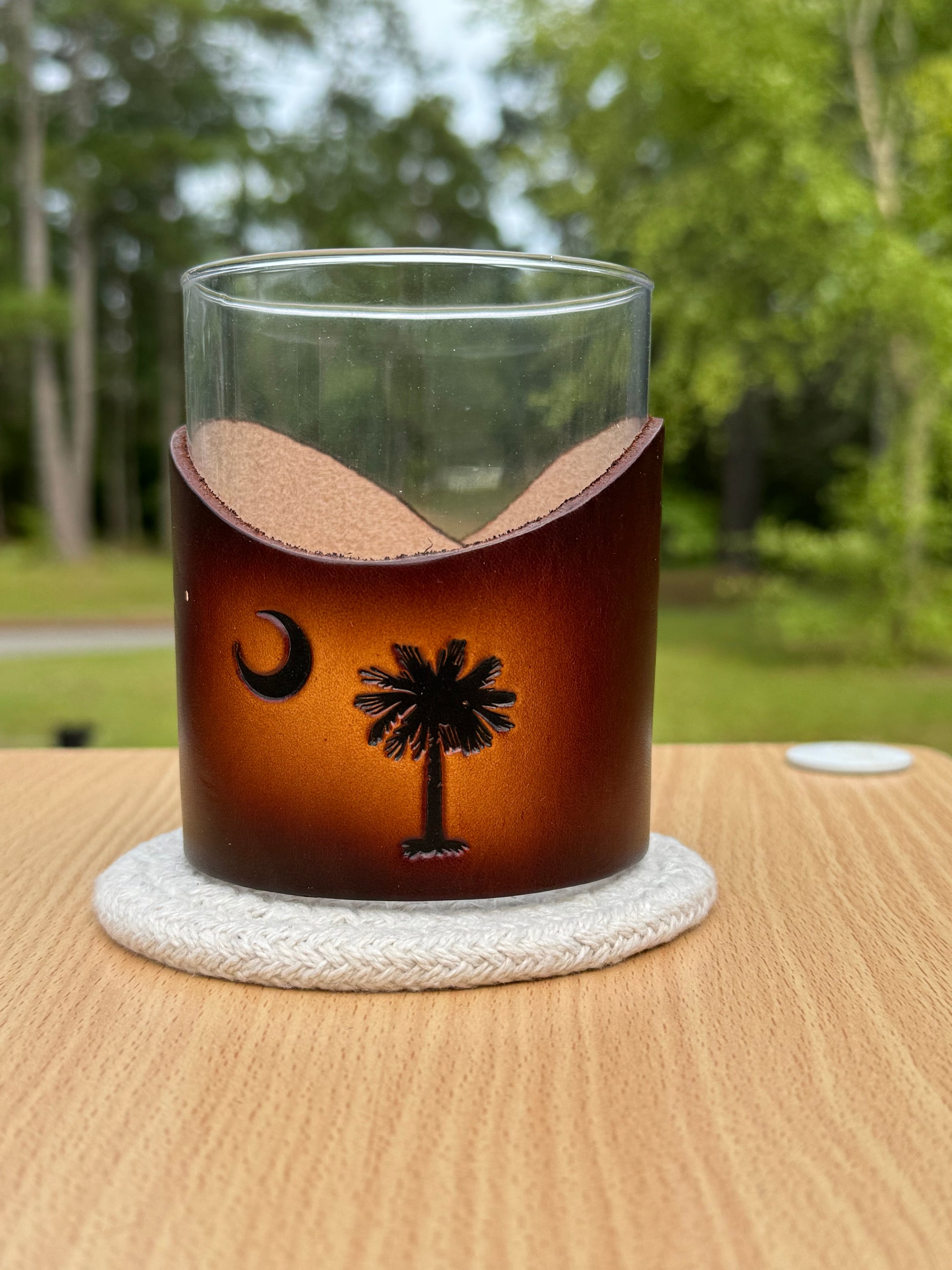 12 oz rocks glass with leather wrap. Wrap has palmetto tree with a cresent moon engraved on front of leather wrap