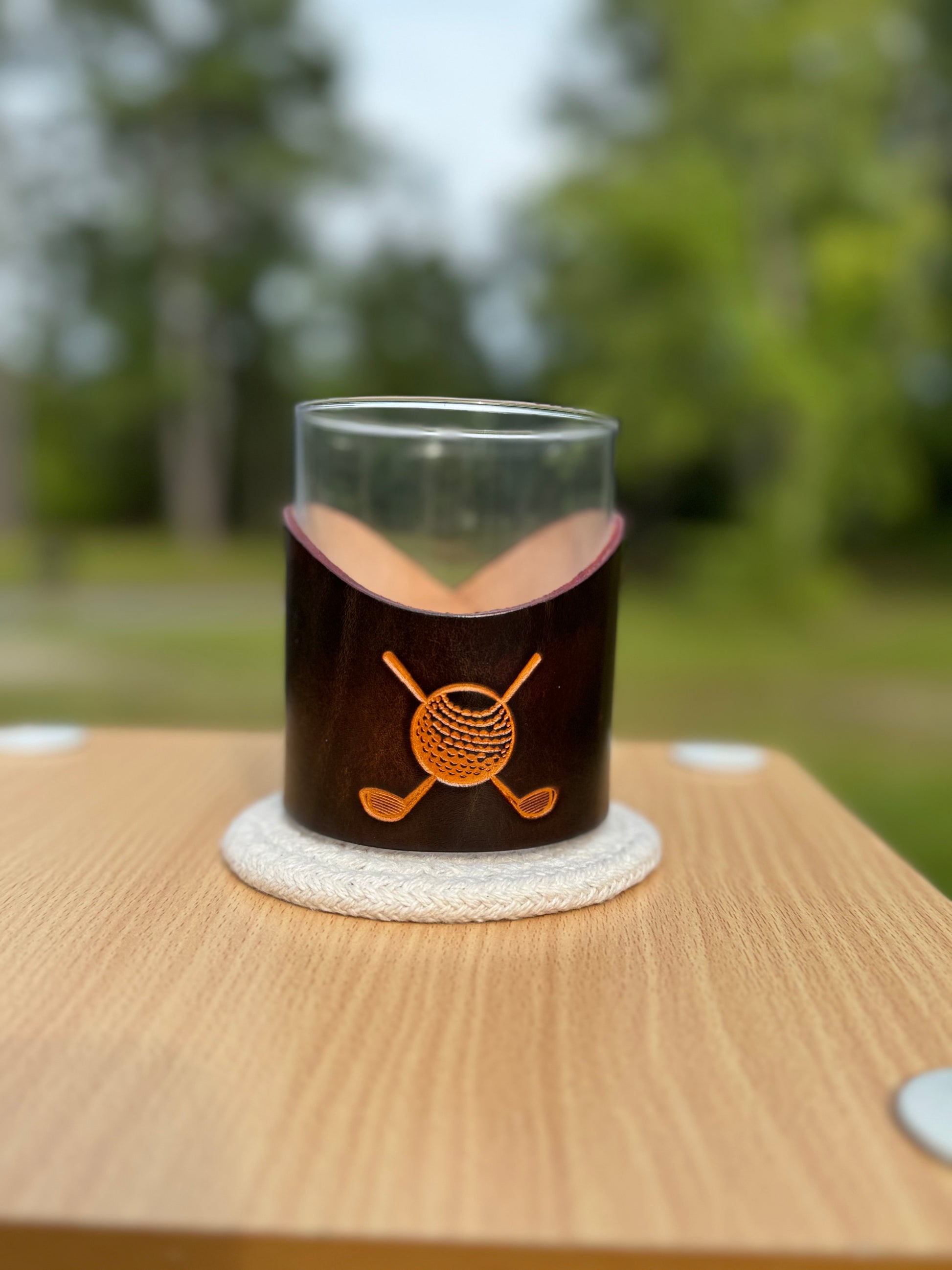 12 oz rocks glass with leather wrap. Wrap has golf clubs with golf ball  engraved on front of leather wrap