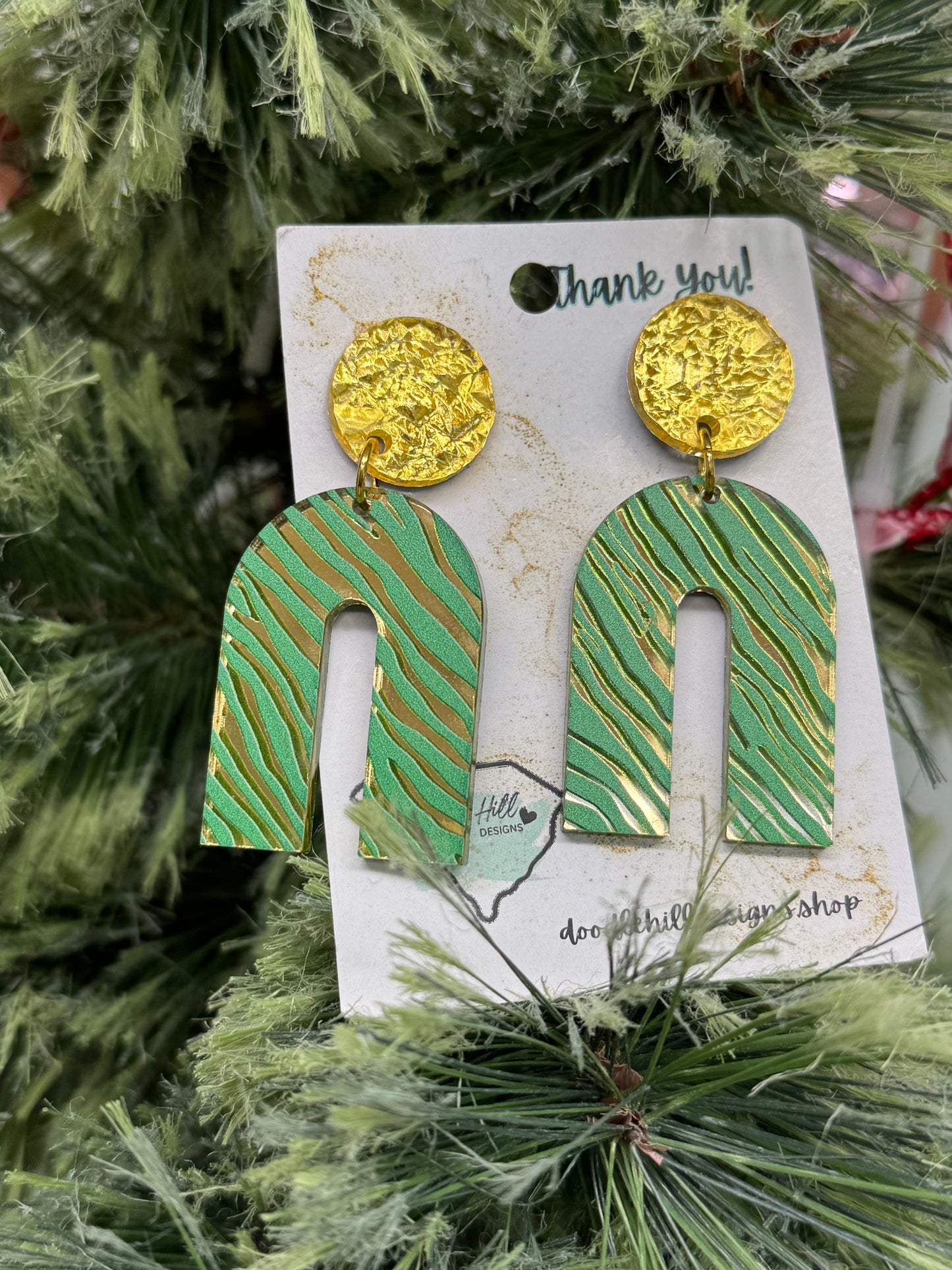 rainbow shapped gold mirror earrings with a green zebra print. Post are gold textured