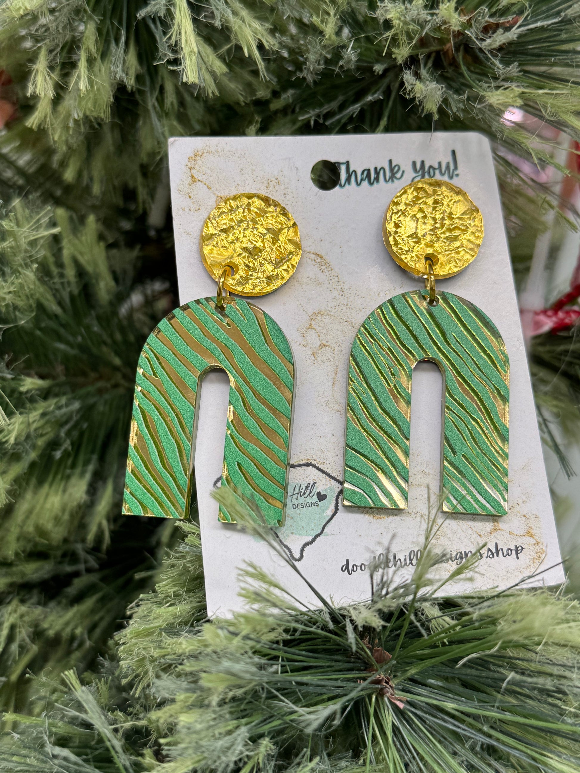 rainbow shapped gold mirror earrings with a green zebra print. Post are gold textured