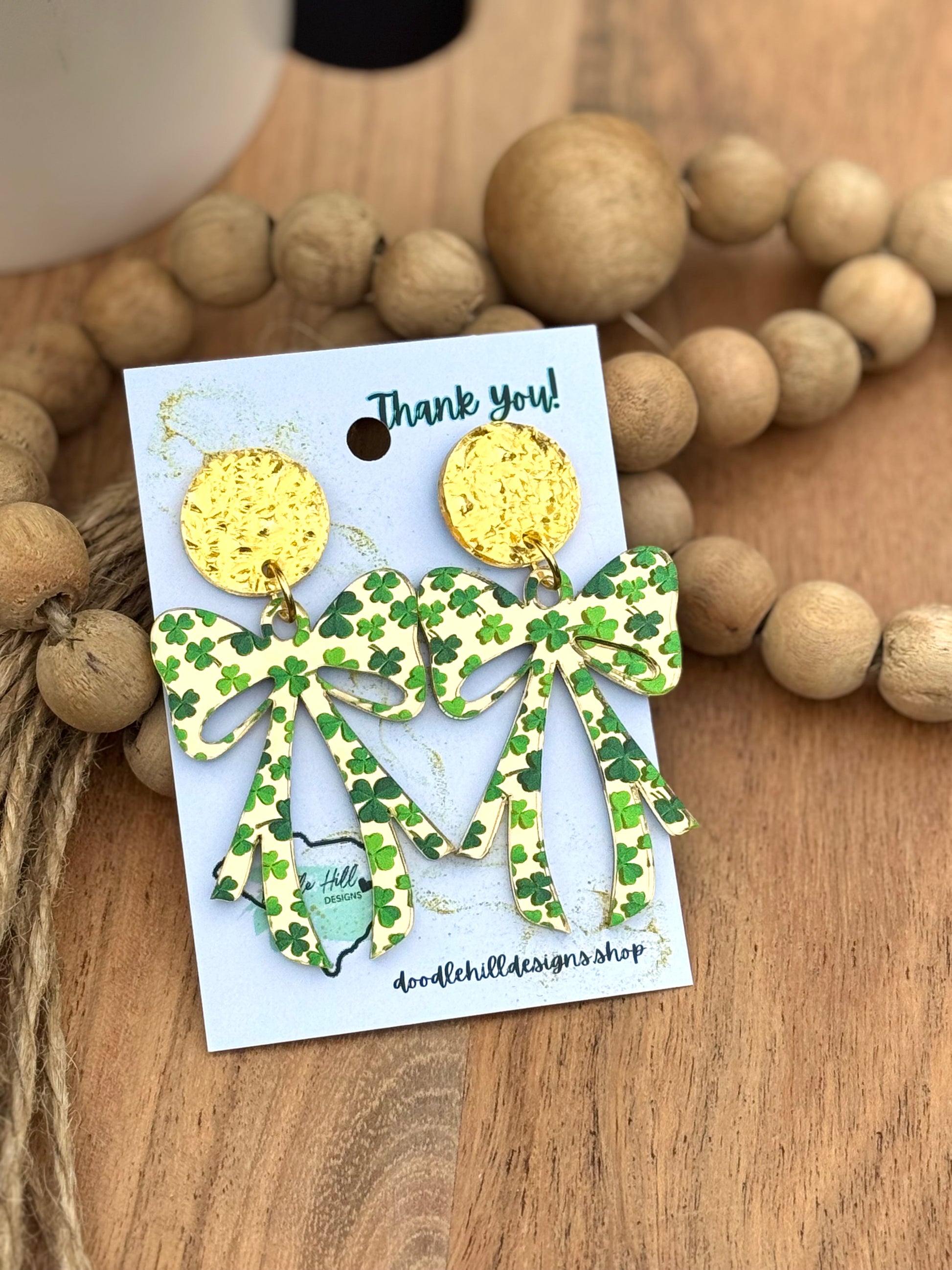 "Shamrock bow earrings for St. Patrick’s Day – lightweight acrylic with green clover print. Festive dangle earrings with gold textured posts, perfect for Irish-themed outfits, lucky charm accessories, and holiday celebrations. Trendy statement earrings for March 17 events and everyday wear."