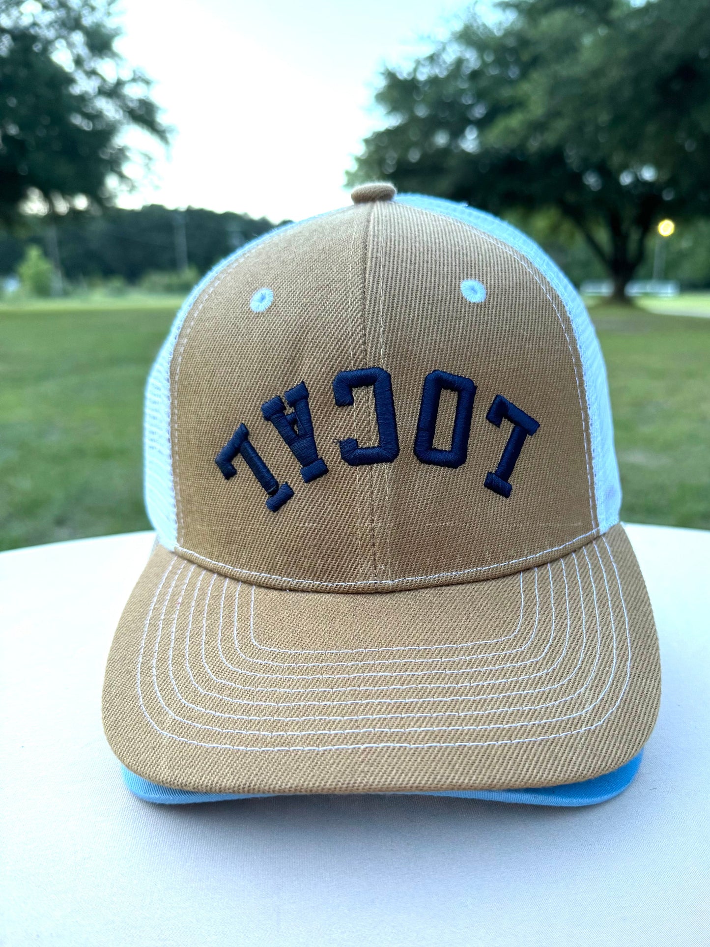 Beigh structured adjustable ball cap with the word local embroidered across the top in Navy. The word is upside down on the hat which is the new trend 